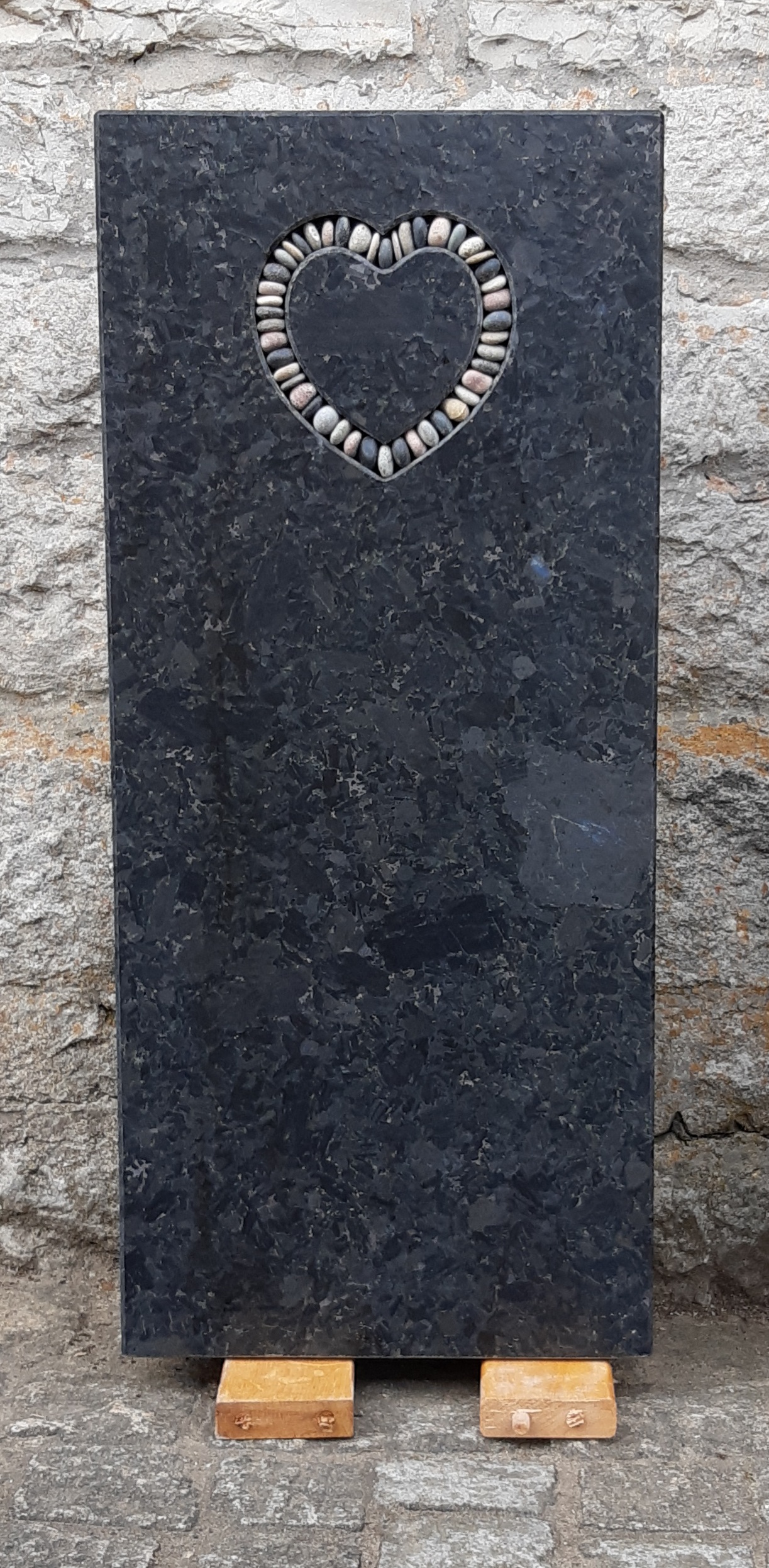 Schwarzer Grabstein mit Herzform aus Kieseln