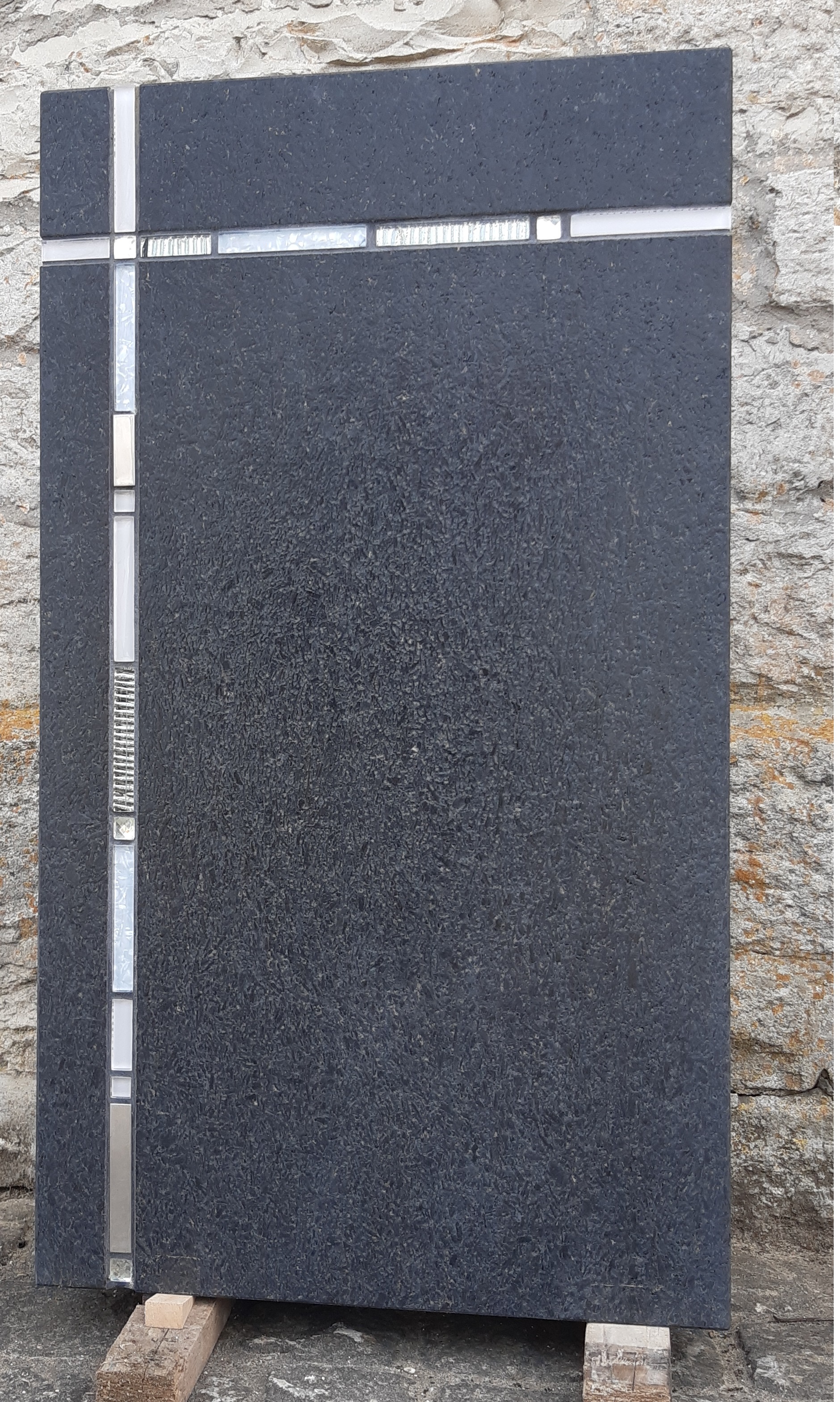 Schwarzer Grabstein mit Metalleinlage