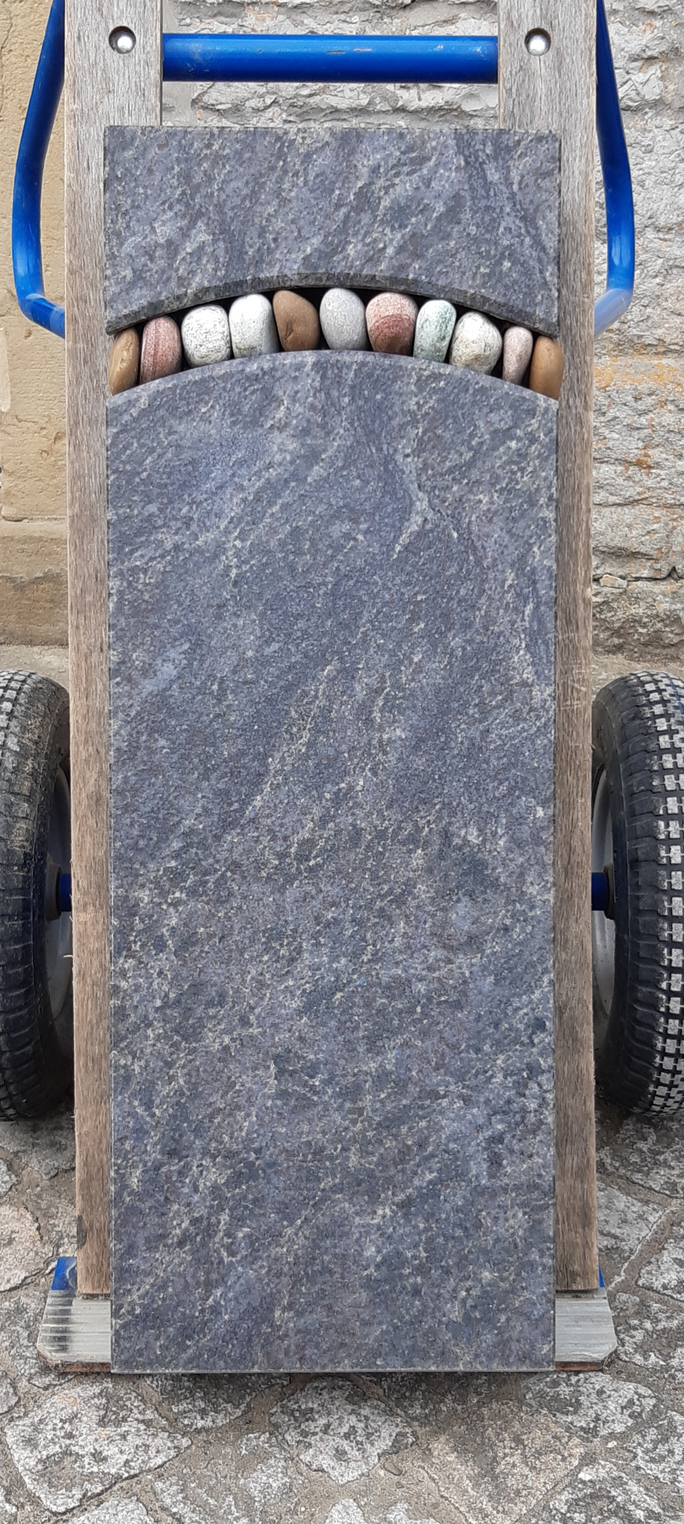 Grauer Grabstein mit Kieselbogen