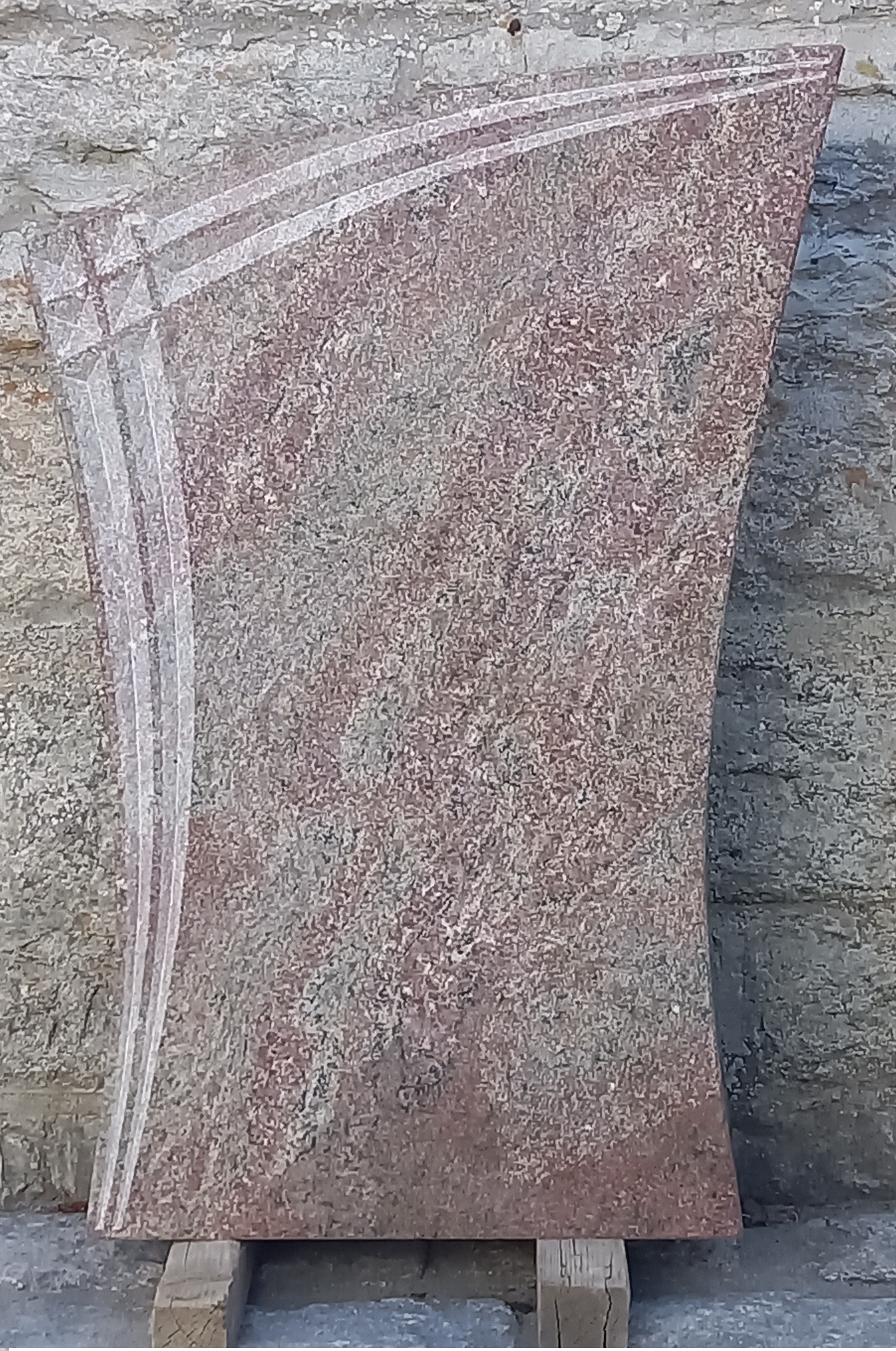 Roter Grabstein mit geschwungenem Linienmuster