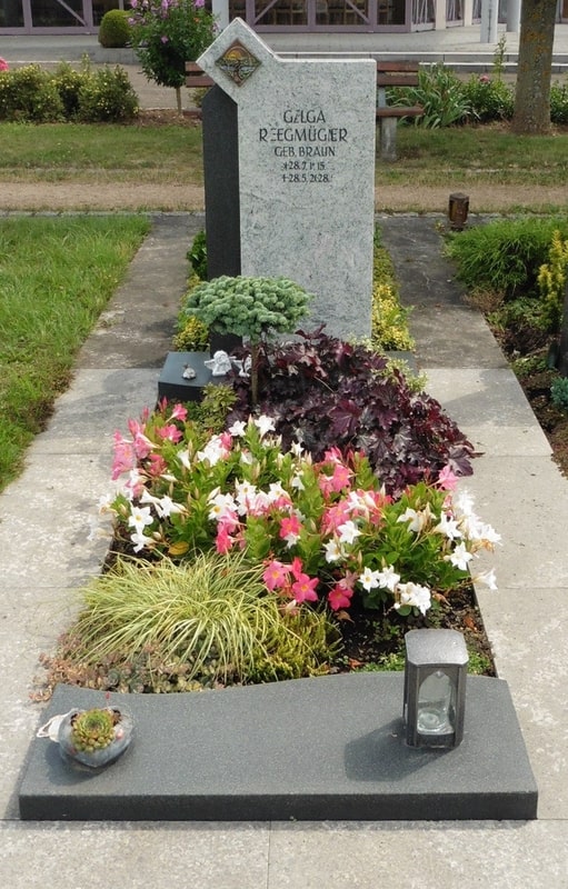Hellgrauer Grabstein mit Bodendeckerpflanzen