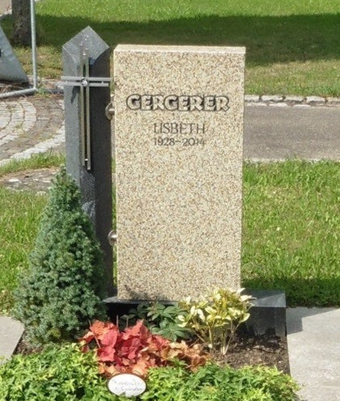 Beiger Grabstein mit Metallkreuz
