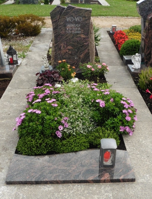 Dunkler Grabstein mit Blumenbeet